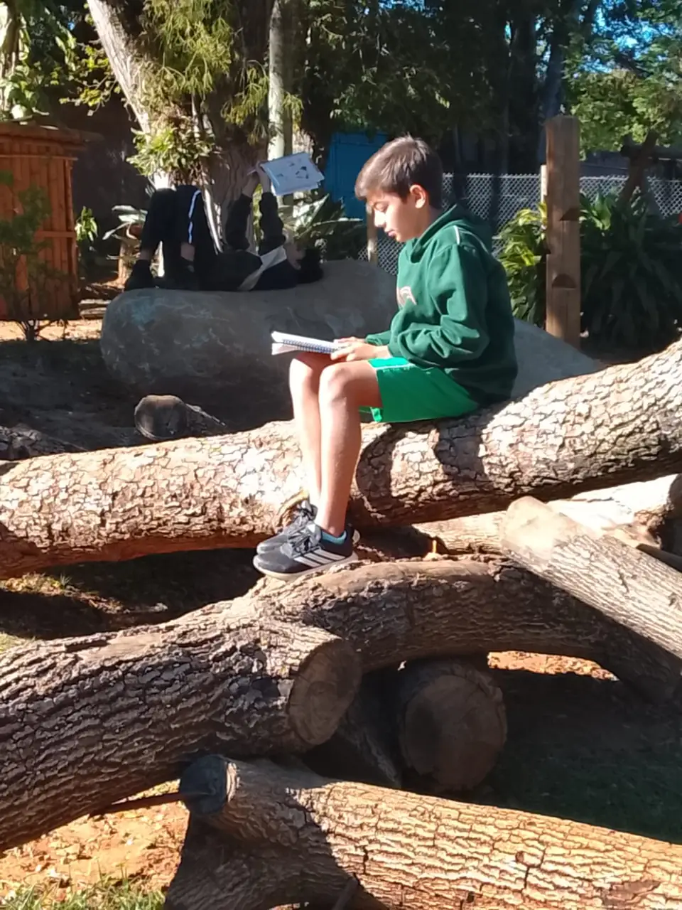 Estudante lendo e escrevendo sentado em um tronco
